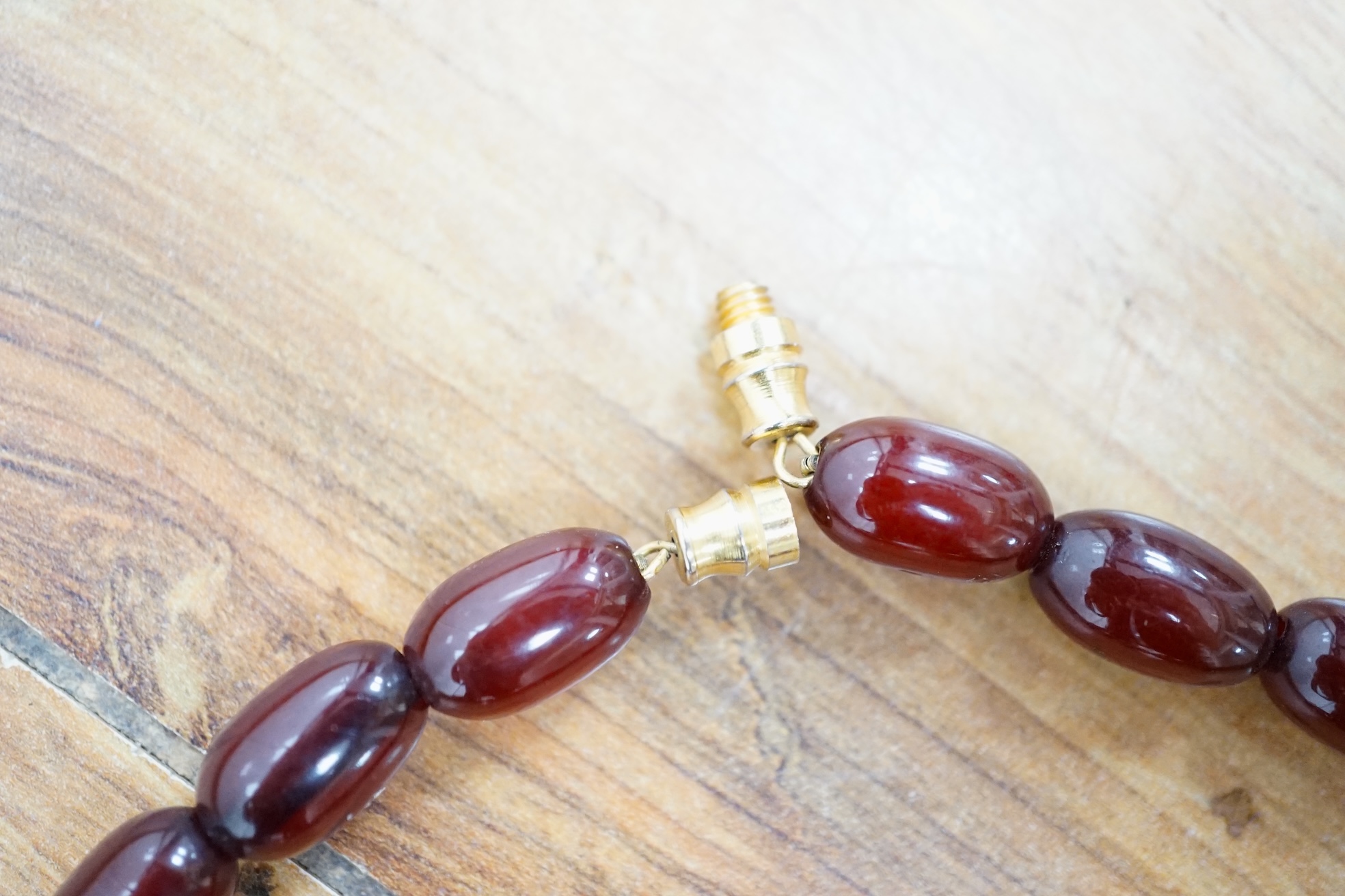 Two single strand simulated cherry amber bead necklaces, including one graduated string, 38cm, gross weight 173 grams. Condition - fair